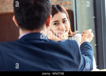 Two young asian couple of lover. Beautiful love couple Man and woman dating in cafe enjoy the time spent together with cell phone . Flirting date peop Stock Photo