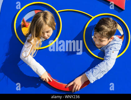 Boy and girl touching with the hand. Kids put head through the hole at playground. Couple young kids love. Love and Friendship concept. Stock Photo