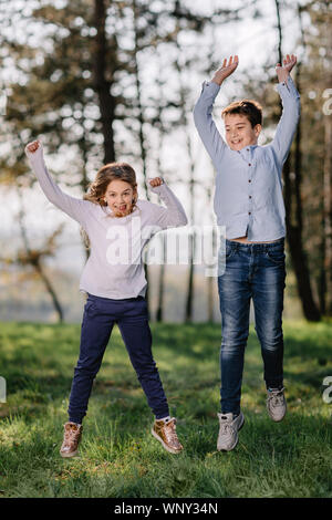 Boy and Girl jumping and enjoy in nature. Happy kids playing in park. Stock Photo