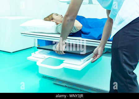Medicine concept ,Technician Doctor male radiologist with colleague setting up machine to take female patient in x-ray room Stock Photo