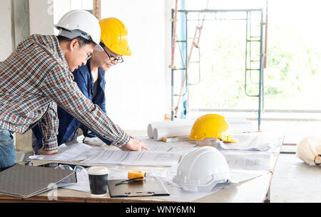 Happiness smile professional businessman consulting with engineering/ architecture in construction renovate building site. Successful team of male coo Stock Photo