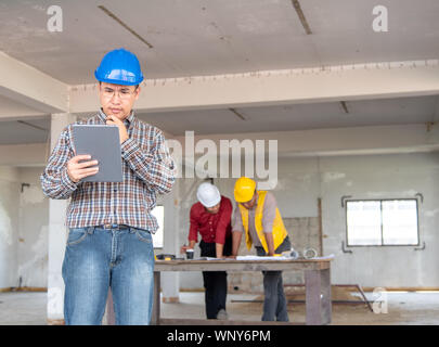 Happiness smile professional businessman consulting with engineering/ architecture in construction renovate building site. Successful team of male coo Stock Photo