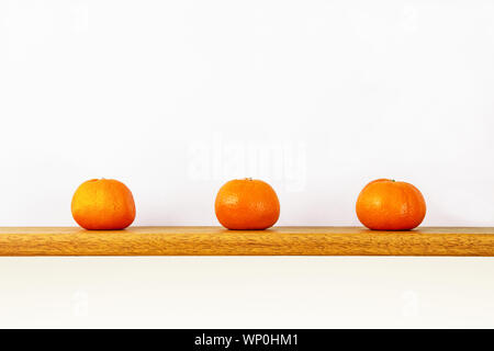 Three oranges on a shelf isolated against a white background Stock Photo