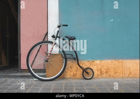 Penny Farthing bicycle, mountain model leaning on a blue wall. Penny Farthing current model Stock Photo