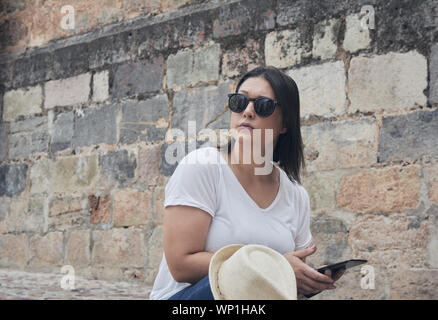 portrait of tourist girl sitting using her smart phone on the stone staircase Stock Photo