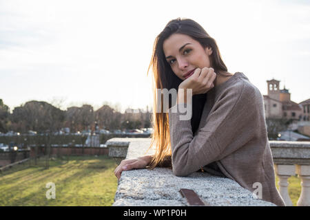 Portrait of woman resting her head on her hand while leaning on stone Stock Photo