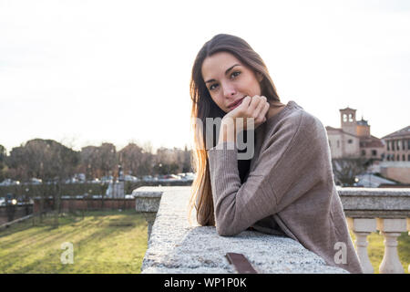 Portrait of woman resting her head on her hand while leaning on stone Stock Photo