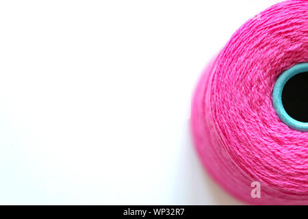 Bobbin of fuchsia threads for hand and machine knitting close-up. Background top view, space for text. Stock Photo