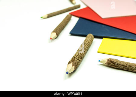 Colored pencils made from branches of trees and colored books isolate on white background. Stock Photo
