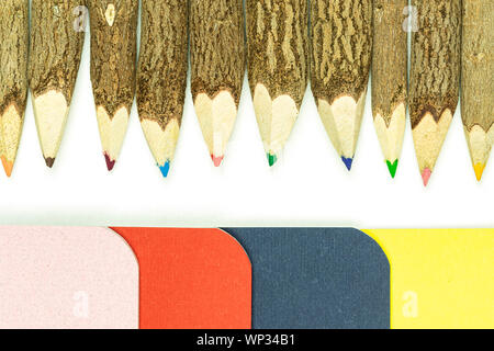 Colored pencils made from branches of trees and colored books isolate on white background. Stock Photo