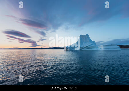 Icebergs in front of the fishing town Ilulissat in Greenland. Nature and landscapes of Greenland. Travel on the vessel among ices. Seascape