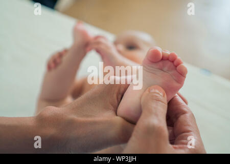 Small feet of the baby in the women's hands. The concept of motherhood, care and warmth Stock Photo
