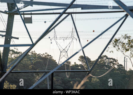 High voltage power lines crossing a valley near Sydney in New South Wales, Australia with aircraft warning spheres attached to the power lines. Stock Photo