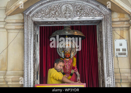 Lord hanuman statue and priest at a temple, Chhatarpur Temple, Chhatarpur, New Delhi, India Stock Photo