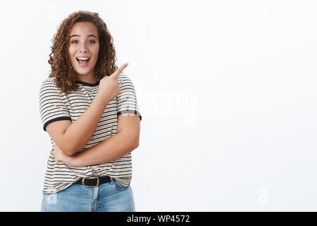 Hey check this out. Lively enthusiastic confident plump young girl pointing interesting link showing you awesome promo indicating upper right corner s Stock Photo