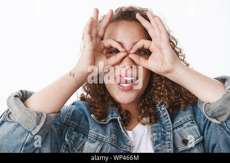 Why so serious. Attractive funny cute silly curly-haired chubby girl fool around making faces stick tongue hold circles eyes mask superhero grimacing Stock Photo