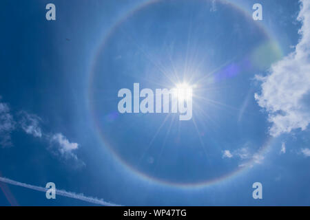 The silhouette sun halo at noon with the blue sky cloud, the beam, light and lens flare effect tone background. Stock Photo