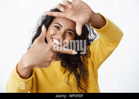 Girl artist searching inspiration in surroundings, showing frames gesture and looking through, make form shape of camera lens and smiling broadly, sta Stock Photo