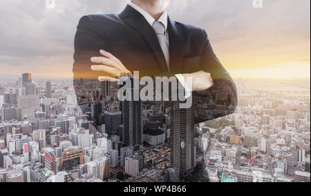 Business leader in black suit with arm crossed, Double exposure city in sunset Stock Photo