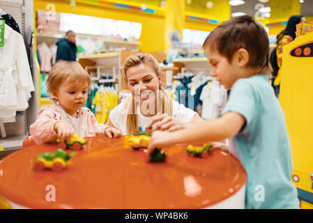 Mother with little children playing in kids store Stock Photo