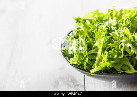 Fresh salad endivia in black bowl on wooden table Stock Photo