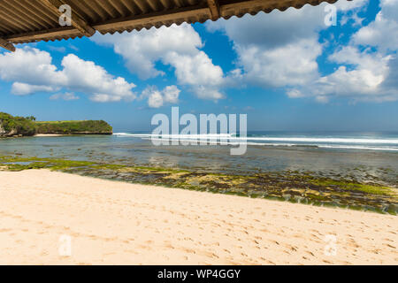 A perfect wave breaking along a reef point off a beautiful tropical beach in Asia - scenic nature landscape travel image with copy space for text. Stock Photo