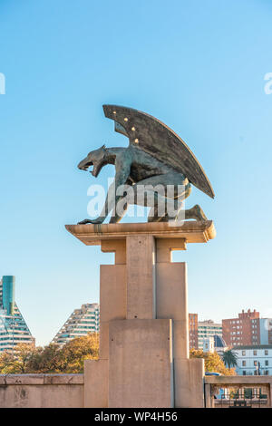 VALENCIA, SPAIN - February 16, 2019: Sculpture of guardian Gargoyle over Pont del Regne (bridge of the Kingdom), against blue sky. Buildings on backgr Stock Photo