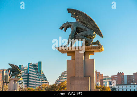 VALENCIA, SPAIN - February 16, 2019: Sculpture of guardian Gargoyle over Pont del Regne (bridge of the Kingdom), against blue sky. Buildings on backgr Stock Photo