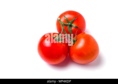 Closeup of three red fresh tomatoes in a pile in a green stalk on white isolated background, top view. Healthy diet, vegetarian food Stock Photo