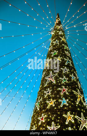 green decorated christmas tree with colored stars hanging on blue backgrounds Stock Photo