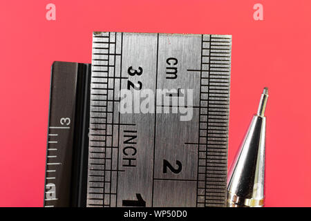 Rulers and mechanical pencil macro image in red background. High quality steel technical drawing tools with different measuring scales. Stock Photo