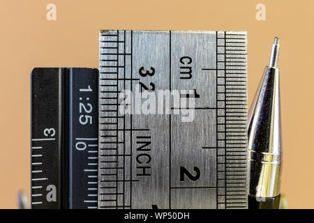 Rulers and mechanical pencil macro image in yellow background. High quality steel technical drawing tools with different measuring scales. Stock Photo