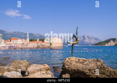 Statue of a ballerina Dancer of Budva against the Old Town of Budva. Panoramic view. Medieval cities in the Mediterranean. Resort of Adriatic Riviera. Stock Photo