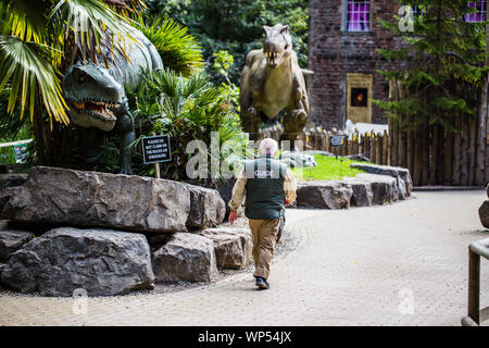 A guide at Wookey Hole caves Dinosaur part walking past the exhibits. Stock Photo