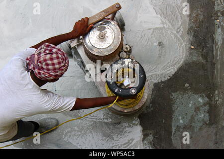 Man operating a floor polishing machine to make newly laid stone flooring smoother in New Delhi, India Stock Photo