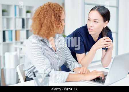 Two young multicultural female managers or office workers organizing work Stock Photo