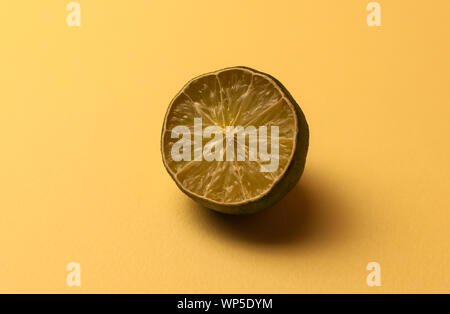 The concept of ugly fruits and citrus fruits. Half of the sliced lime has dried up, deteriorated on a beige background. Selective focus with a hard Stock Photo