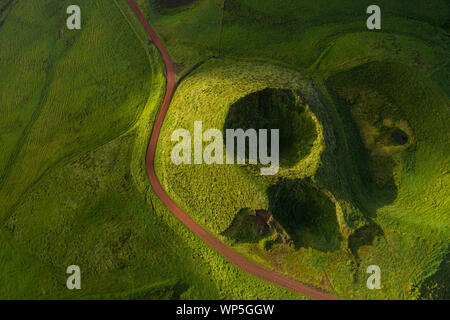 Aerial top view showing a small volcanic crater and road in the mountains of the San Jorge Island in the Azores, near pico de la Esperanza, Portugal Stock Photo