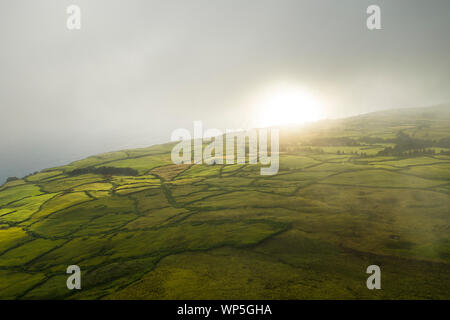 Aerial image showing a morning misty sunrise over the typical countryside of Sao Jorge Island, Azores. São Jorge is an island situated in the central Stock Photo