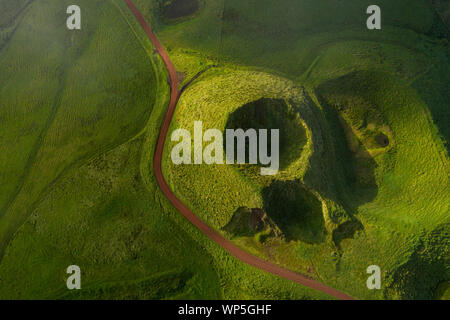 Aerial top view showing a small volcanic crater and road in the mountains of the San Jorge Island in the Azores, near pico de la Esperanza, Portugal Stock Photo