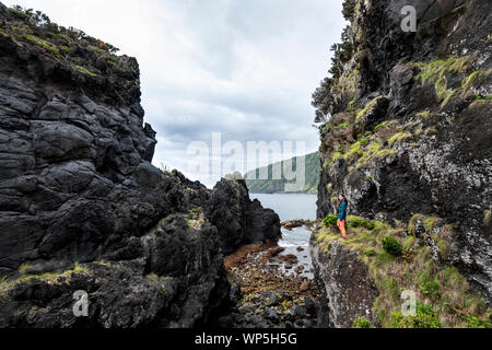 Young woman walking through the lava debris field landscape of Poça Simão Dias, near the natural pools of Fajã do Ouvidor at the north coast of the Sa Stock Photo