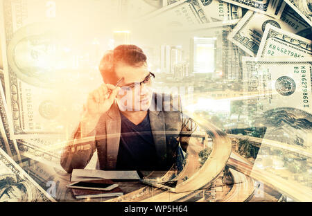 businessman holding a pen thinking sitting at his desk behind his new notebook isolated on white background. Stock Photo