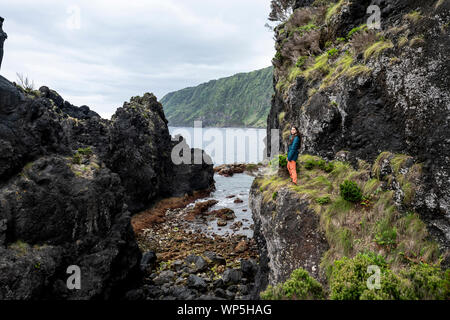 Young woman walking through the lava debris field landscape of Poça Simão Dias, near the natural pools of Fajã do Ouvidor at the north coast of the Sa Stock Photo