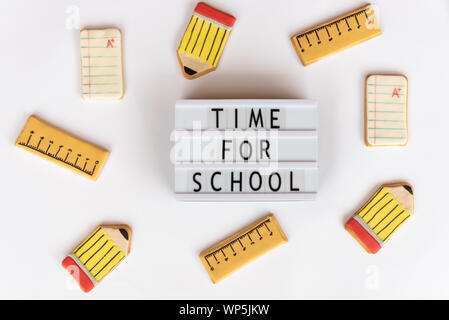 Back to school concept. The text time for school in a lightbox, on a white background and surrounded by fondant cookies with designs related to school Stock Photo