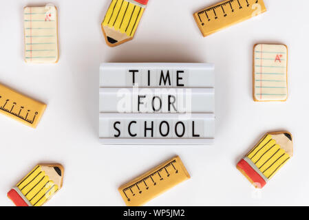 Back to school concept. The text time for school in a lightbox, on a white background and surrounded by fondant cookies with designs related to school Stock Photo