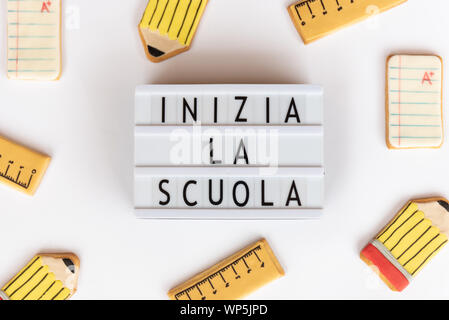 Back to school concept. The text inizia la scuola  in a lightbox (back to school in italian),  on a white background and surrounded by fondant cookies Stock Photo