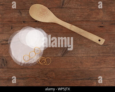 Traditional home made jam making equipment, wooden spoon and wax paper and cellophane covers. On wooden background. Stock Photo