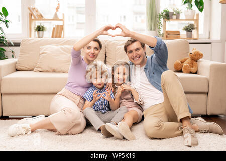 Happy parents and two adorable siblings making heart shape with fingers Stock Photo
