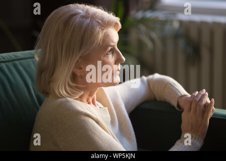 Pensive elderly woman look in distance thinking or mourning Stock Photo