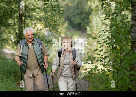 Cheerful mature active couple enjoying trekking in the forest or park Stock Photo